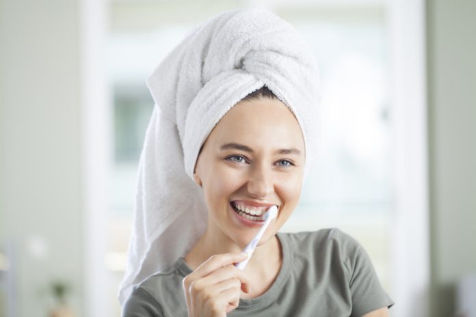 Vrouw poetst tanden met handdoek op hoofd